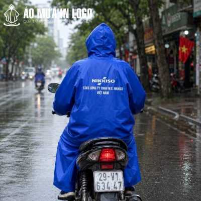 Góc nhìn từ phía sau người lái xe máy mặc áo mưa AM-DB07 in logo Nikkiso nổi bật trên đường phố Hà Nội
