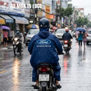 Logo Ford nổi bật trên lưng người mặc khi di chuyển bằng xe máy dưới trời mưa tại một thành phố Việt Nam.