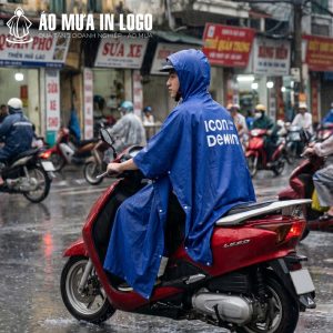 Người đàn ông mặc áo mưa AM-CC05 đang lái xe máy trên đường phố ngày mưa, logo thương hiệu được nhìn thấy rõ từ phía trước.
