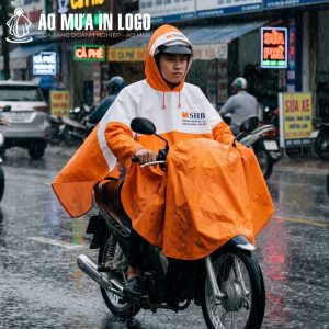 Một người đàn ông đang lái xe máy dưới trời mưa, chiếc áo mưa SHB che phủ cả phần đầu xe, thể hiện tính năng bảo vệ tối ưu.