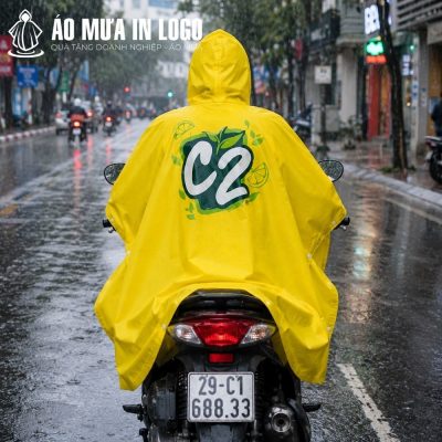 Góc chụp từ phía sau người lái xe máy mặc áo mưa màu vàng C2 lộ rõ logo in khổ lớn ở mặt lưng