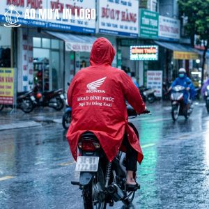 Góc nhìn từ phía sau cho thấy logo và thông điệp thương hiệu được in sắc nét, nổi bật trên lưng áo mưa khi di chuyển trên đường