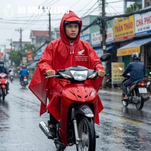 Người dùng nam mặc áo mưa khi đang lái xe máy dưới trời mưa, thể hiện tính ứng dụng thực tế và sự thoải mái khi vận hành xe.